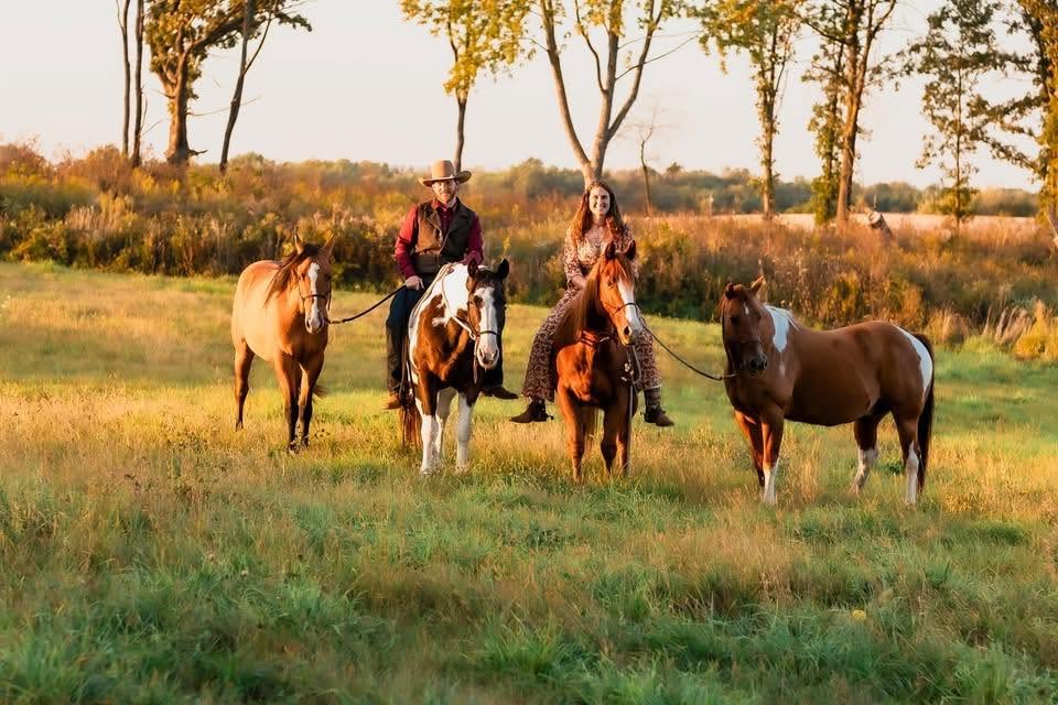 Two riders and four horses in a golden field at Rich Earth Ranch